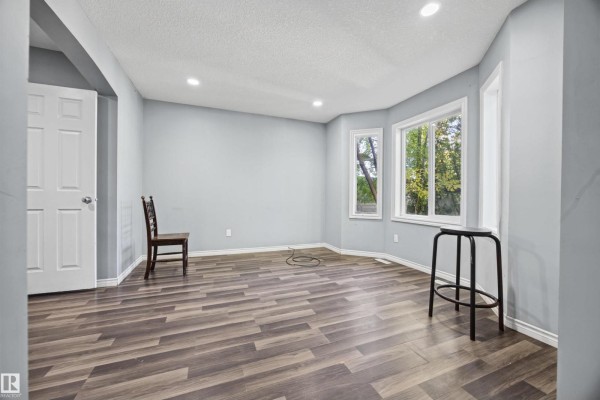 Living room with grey walls, bay windows, and dark wood laminate flooring. - 9626 106 Av Nw, Edmonton