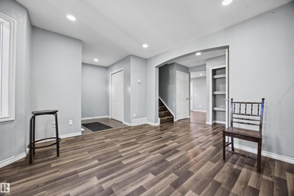 Living room looking back towards the entryway and an arched doorway leading to stairs and hallway. - 9626 106 Av Nw, Edmonton