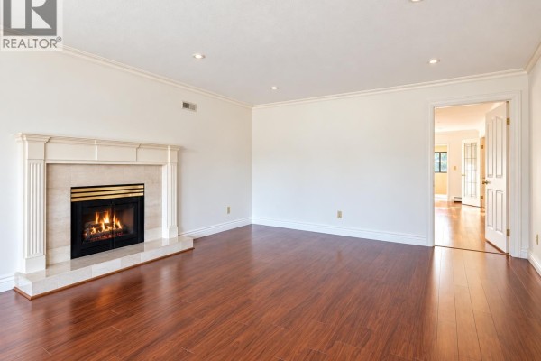 Spacious living area with a fireplace, hardwood floors, and sliding glass doors to the outside. - 963 Merritt Street, Coquitlam