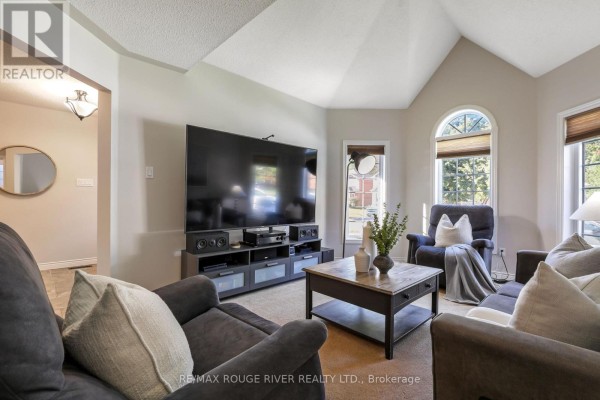 Living room with a large television, vaulted ceiling, arched window, and plush seating. - 965 Ridge Valley Drive, Oshawa
