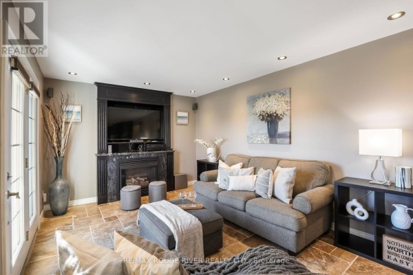 Family room with a fireplace, television, grey sofa, ottoman, and French doors. - 965 Ridge Valley Drive, Oshawa