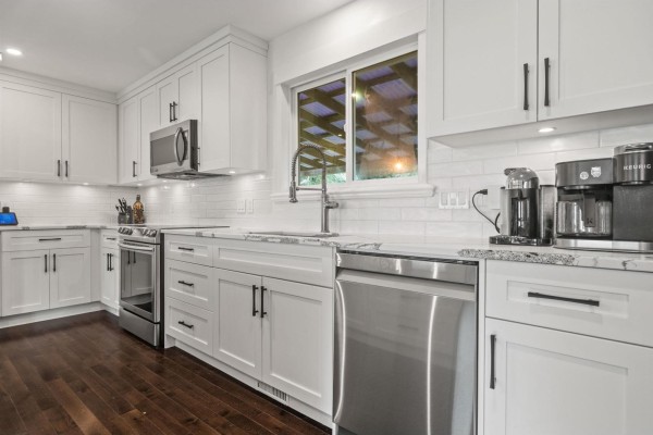 Close-up of a white kitchen sink, dishwasher, and granite countertops with subway tile backsplash. - 9650 Aberdeen Crescent, Rosedale, Rosedale