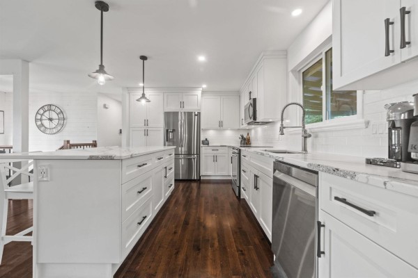 Spacious white kitchen with an island, stainless steel refrigerator, and pendant lighting. - 9650 Aberdeen Crescent, Rosedale, Rosedale