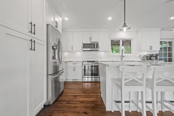View of a white kitchen with a large island, dark floors, and modern cabinetry. - 9650 Aberdeen Crescent, Rosedale, Rosedale
