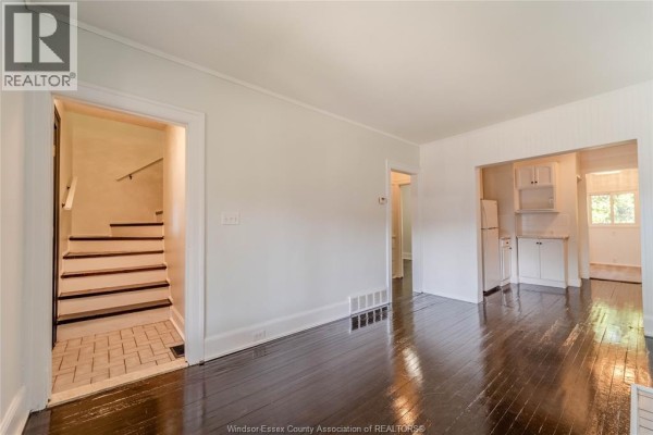 Interior view showing dark hardwood floors, a staircase with white risers and a tiled landing, and doorways to other rooms. - 966 Curry Avenue, Windsor