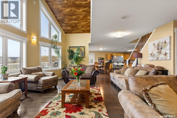 Open-concept living and dining area with vaulted wood ceiling and staircase. - 966 Tatanka Drive, Buffalo Pound Lake