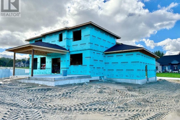 Side view of a house under construction, wrapped in blue, on a dirt lot with tire tracks. - 968 Bogdanovic Way, Huron Kinloss