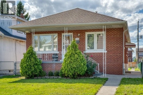 Front exterior of a red brick bungalow with white trim and columns. - 969 Langlois, Windsor