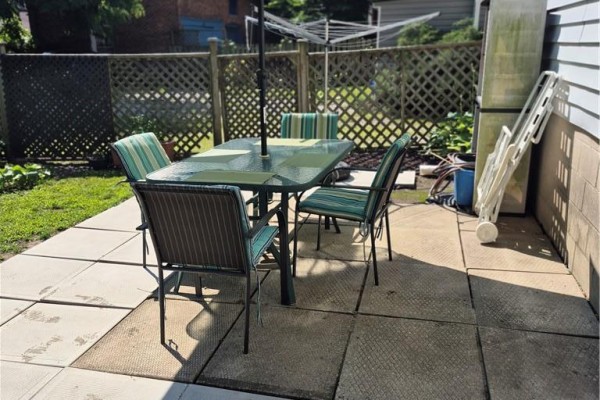 Outdoor patio area with a glass table, chairs, and a clothesline in the background. - 97 Colborne Street S, Simcoe