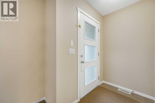Interior view of a beige entryway with a white door with frosted glass panels. - 97 Marine Drive Se, Calgary