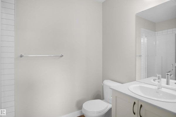 Bathroom with white vanity, toilet, white tiled shower, and a large mirror. - 97 Nerine Cr, St  Albert