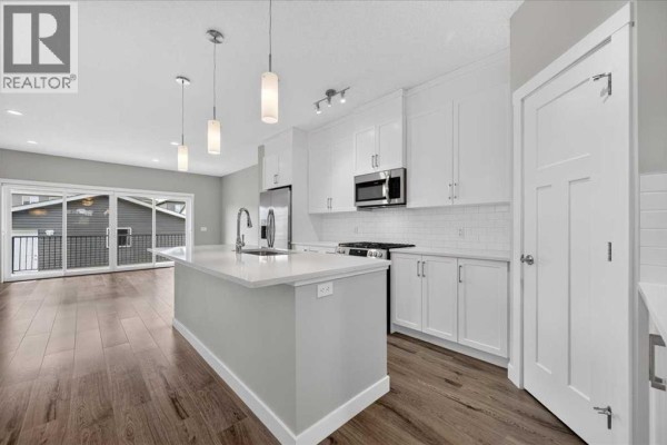 Modern kitchen with white cabinets, stainless steel appliances, and island. - 97 Seton Manor Se, Calgary