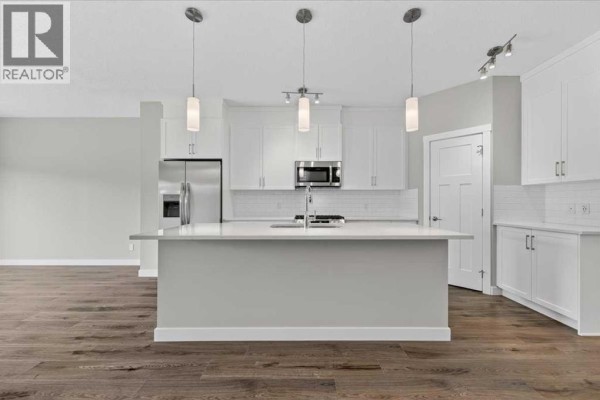 White kitchen with quartz countertops, stainless steel appliances, and island. - 97 Seton Manor Se, Calgary
