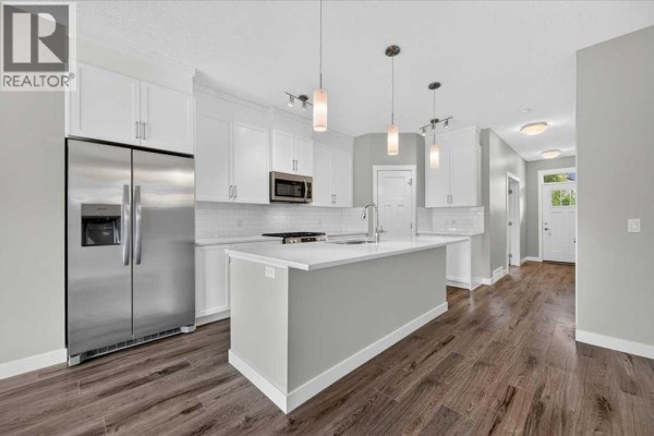 Contemporary kitchen with stainless steel refrigerator, white cabinets, and island. - 97 Seton Manor Se, Calgary