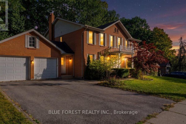 Exterior view of a two-story brick house at dusk, with lights on inside and a starry sky. - 97 Timber Drive, London South