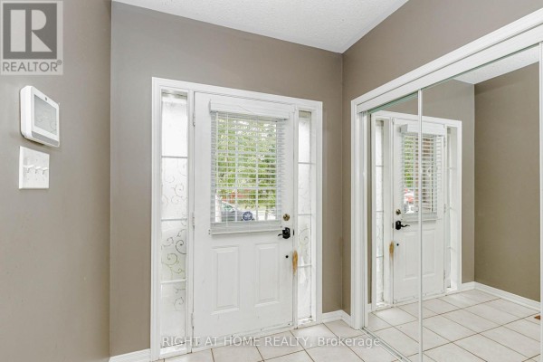 Interior view of a townhouse foyer with a blue front door and mirrored closet doors. - 97 Timbertop Crescent, Brampton