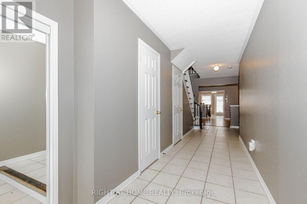 Long, wide townhouse hallway with tiled floors, gray walls, and interior doors. - 97 Timbertop Crescent, Brampton