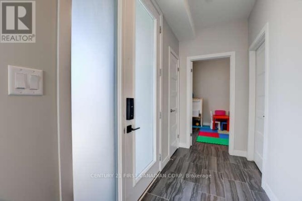 Interior hallway with tiled floor, frosted glass door, and entry to a playroom. - 970 Battery Park, London North