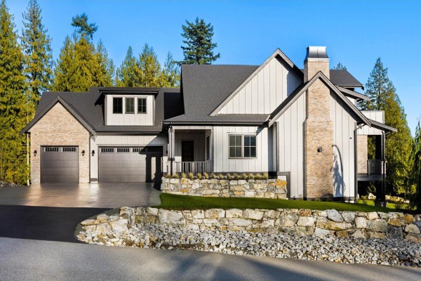 Spacious living area with light wood floors, a black stone fireplace, and large glass sliding doors. - 9700 Gough Terrace, Mission