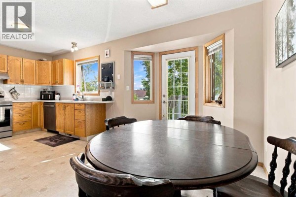 Kitchen with oak cabinets, stainless steel appliances, and a bay window overlooking trees. - 9701 98 Avenue, Sexsmith