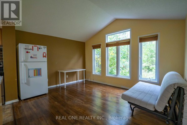 Living space with wood floors, beige and yellow walls, large windows, and a futon couch. - 971 Creekside Drive, Waterloo