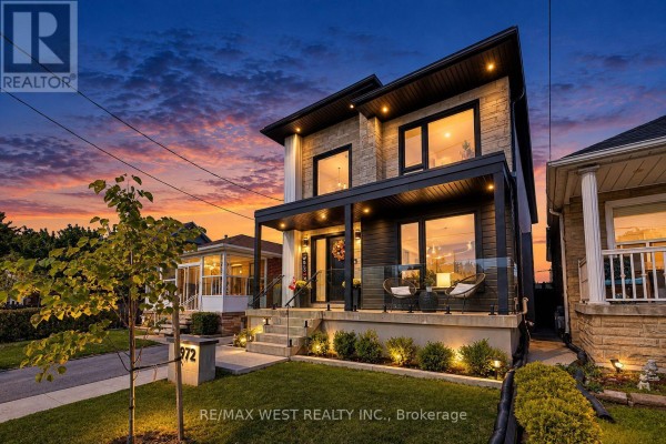 Exterior of the house at dusk, illuminated by outdoor lights with a colorful sunset. - 972 Castlefield Avenue, Toronto