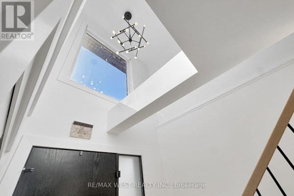 Interior view looking up at a geometric chandelier, a large window, and white walls. - 972 Castlefield Avenue, Toronto