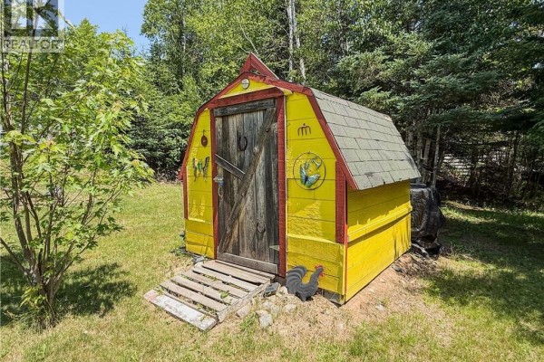 Small yellow shed with a rustic wooden door and decorative horseshoe. - 972 Portage Vale Road, Anagance