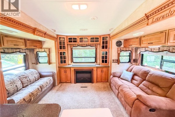 Interior of RV living area with two sofas, fireplace, and wood cabinetry. - 972 Portage Vale Road, Anagance