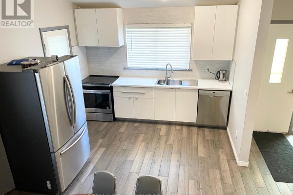 Kitchen area with white cabinets, stainless steel appliances, a window, and light wood-look flooring. - 9740 Keele Street, Vaughan