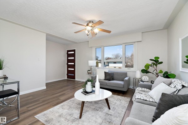 Living room with a grey sofa, a white coffee table, and a wood door. - 9747 66 Av Nw, Edmonton