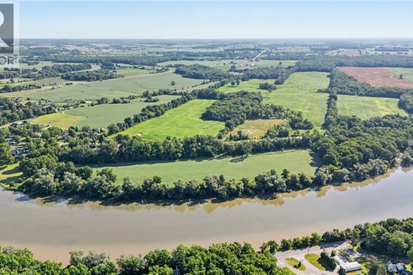 Aerial view of a wide river flanked by green fields and mature trees under a bright sky. - 975 Haldimand Hwy 54, York