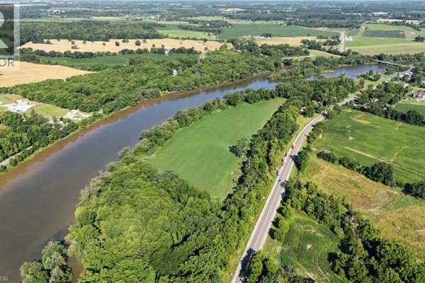 Aerial view of a wide river alongside a road and green fields, with distant houses visible. - 975 Haldimand Hwy 54, York