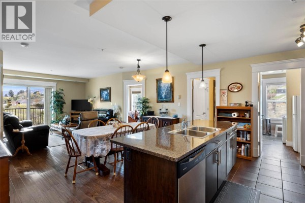 Open concept living and dining area with hardwood floors, granite island, and balcony access. - 975 Victoria Street W Unit# 606, Kamloops
