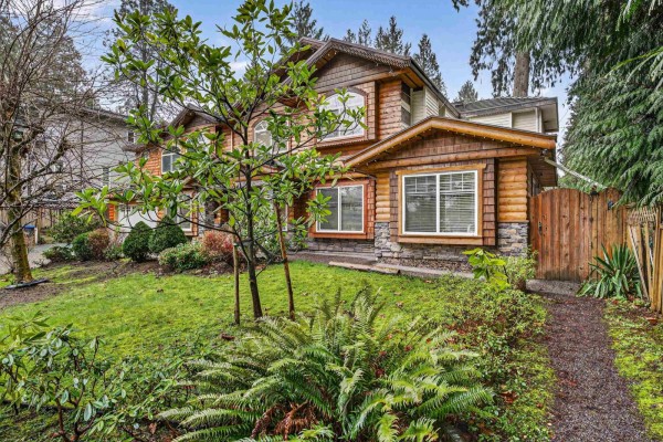 Close-up of the front exterior featuring a stone and log facade with a driveway. - 9766 130a Street, Surrey