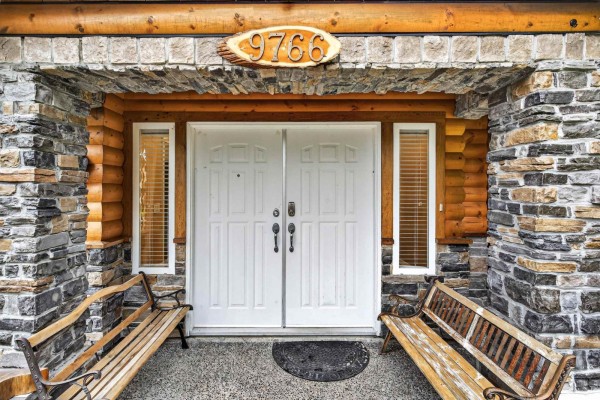 Entrance with double doors, stone pillars, and wooden benches on either side. - 9766 130a Street, Surrey