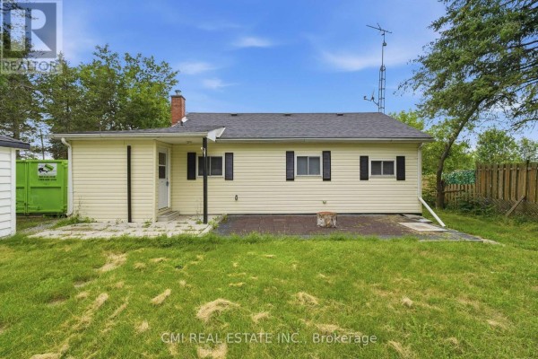 Back of house with vinyl siding, chimney, antenna, fenced yard, and dumpster - 977 County Rd 38 Trent Hills