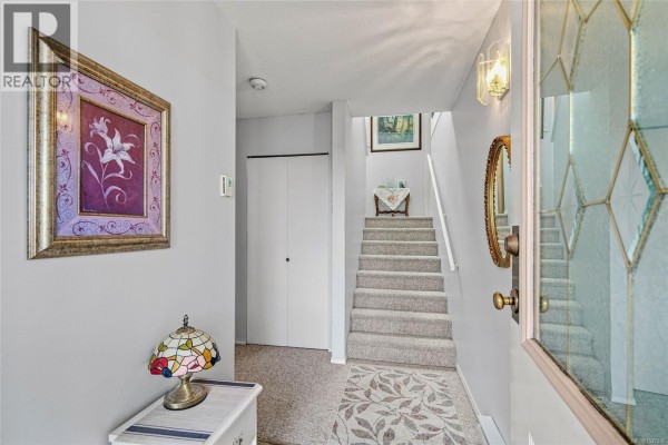 Interior entryway with light grey walls, a staircase, a closet, and decorative artwork and lighting. - 977 Highview Terr, Nanaimo