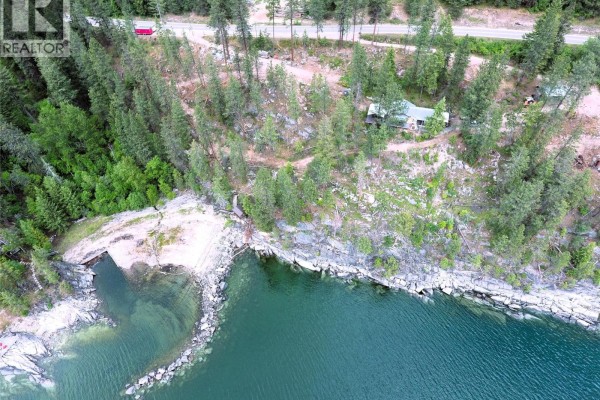 Aerial drone shot of a forested coastline with a small building and a road. - 9779 3a Highway Unit# B, Kuskanook
