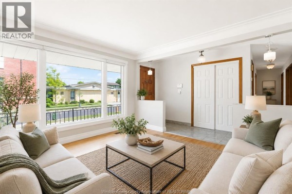 Living room with large windows, beige sofas, a coffee table on a jute rug, and double doors. - 979 Arthur Road Unit# Main, Windsor