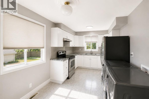 Kitchen with white cabinets, stainless steel appliances, a window, and laundry machines. - 979 Arthur Road Unit# Main, Windsor