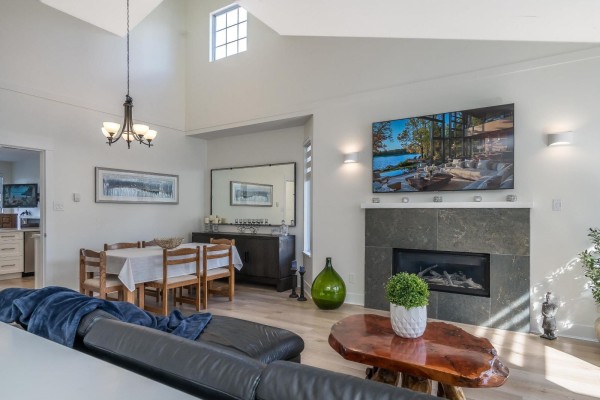 Family room with fireplace, built-in media unit, leather sofa, green armchair, and carpeted floor. - 98 2533 152 Street, Surrey