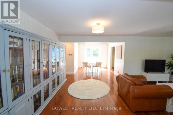Living room with hardwood floors, a leather sofa, and a large built-in grey bookcase. - 98 Delater Street, Niagara On The Lake