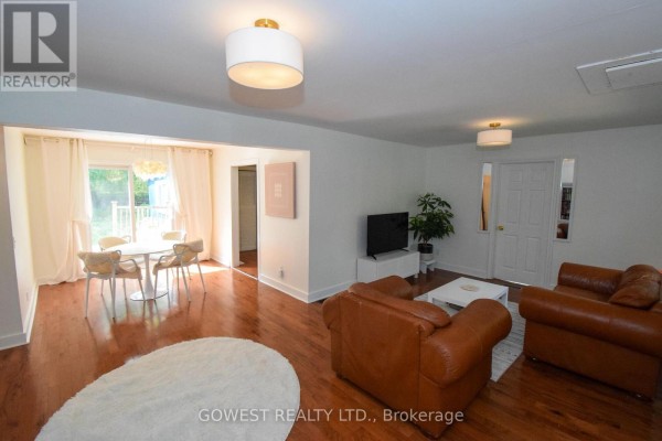 Living and dining area with hardwood floors, a small round dining table, and two brown leather sofas. - 98 Delater Street, Niagara On The Lake