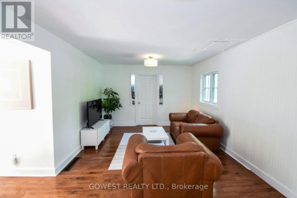 Living room showing two brown leather sofas, a white coffee table, and a white door with windows. - 98 Delater Street, Niagara On The Lake