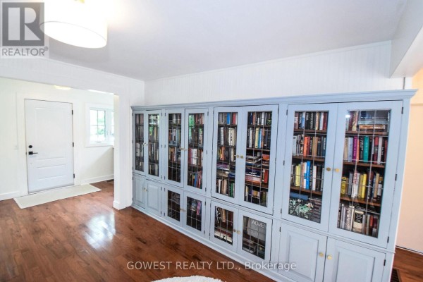 Living room with hardwood floors and a long, grey built-in bookcase filled with books. - 98 Delater Street, Niagara On The Lake