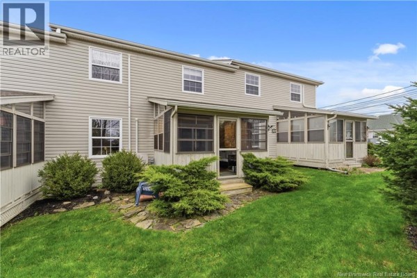 Front entrance of a townhouse with a covered porch, white door, and wreath. - 98 Firmin Crescent, Dieppe