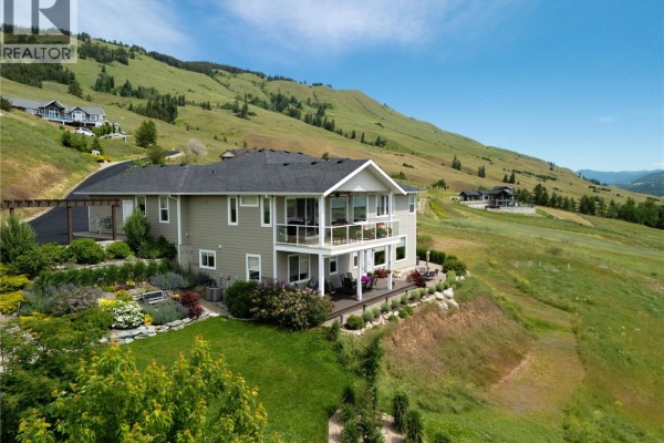 Side view of the home showcasing the balcony and surrounding greenery. - 98 Ranchland Place, Coldstream