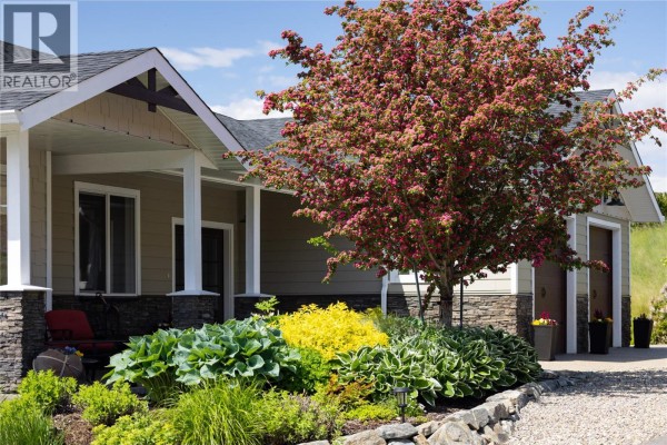 Close-up of the entrance with a flowering tree and stone landscaping. - 98 Ranchland Place, Coldstream