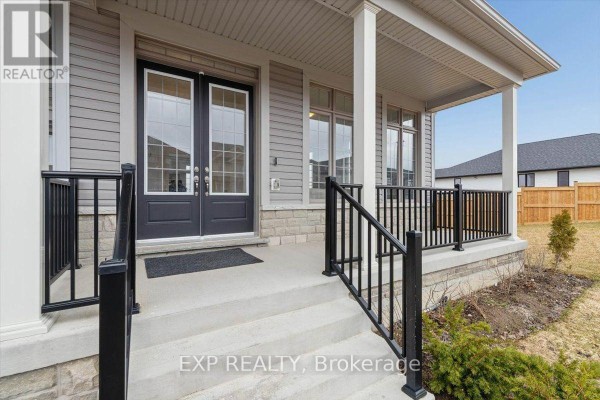 Side view of a light gray two-story house with a large green lawn and treeline. - 98 Rea Drive, Centre Wellington